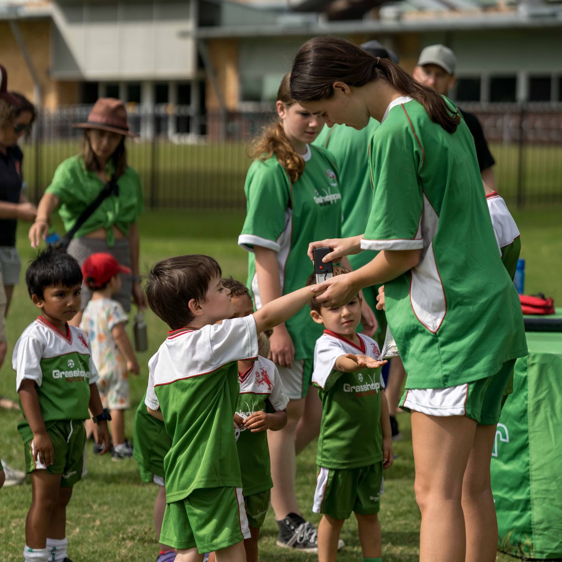 A Grasshopper Soccer coach giving young players a hand stamp at the end of a session