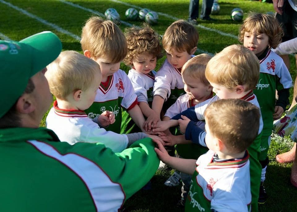 Coach and toddlers with hands in a team huddle